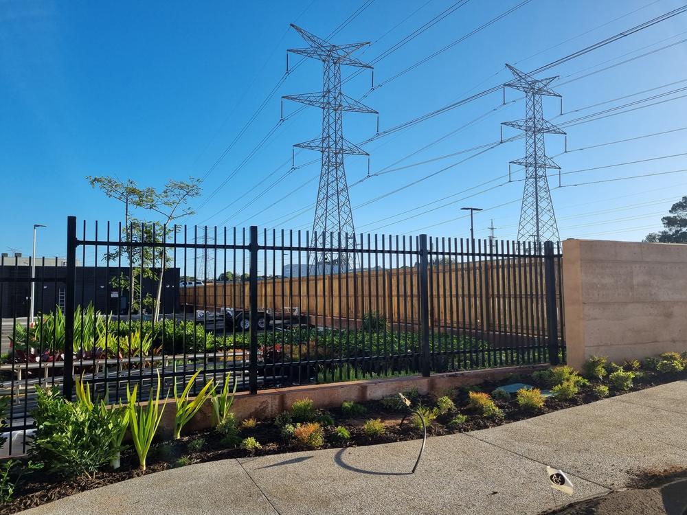 Black aluminium blade fence along a landscaped verge