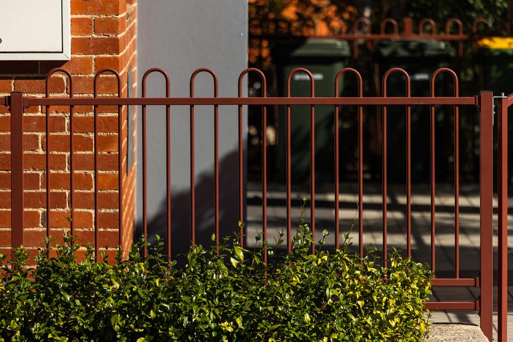 Tubular steel fence with loop tops in front of a brick building