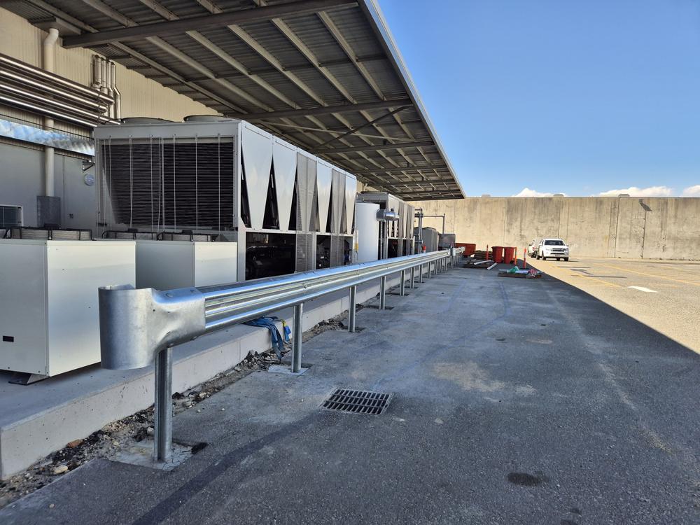 Galvanised guard rail protecting rooftop plant along a warehouse
