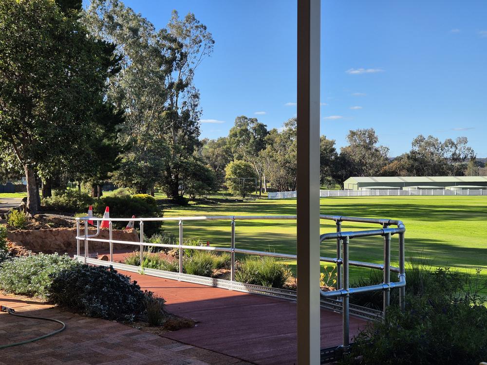 Galvanised handrail along a path beside a sports oval