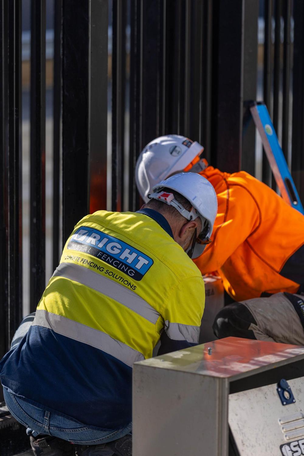 Two RMF technicians in branded hi-vis working on a gate