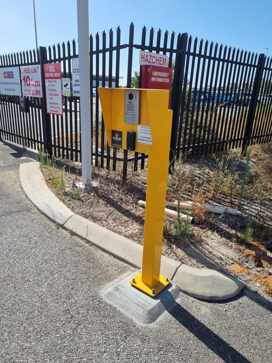 Intercom and card reader pedestal beside a vehicle gate