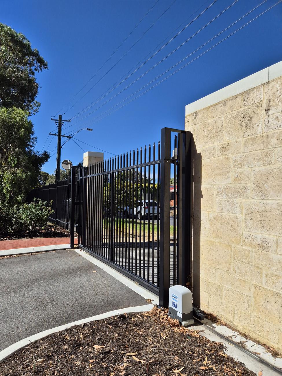 Black Garrison swing gate beside a limestone wall