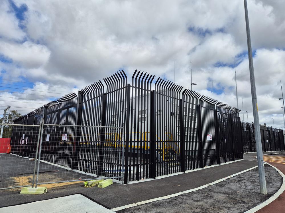 Black palisade fencing with triple-point pales around a compound